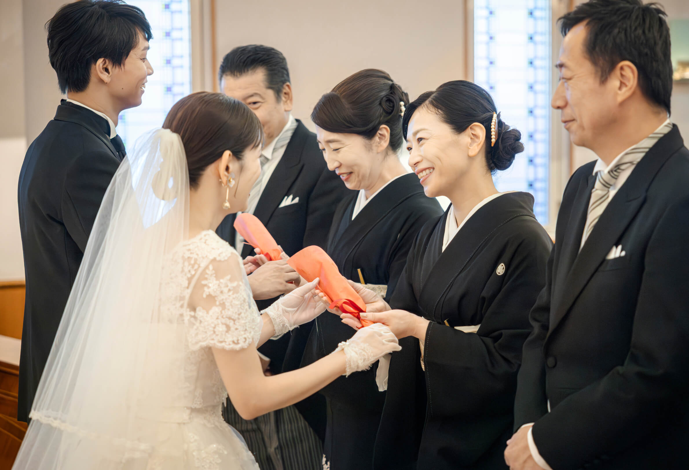両家の家族と祝いの品を交わす新郎新婦
