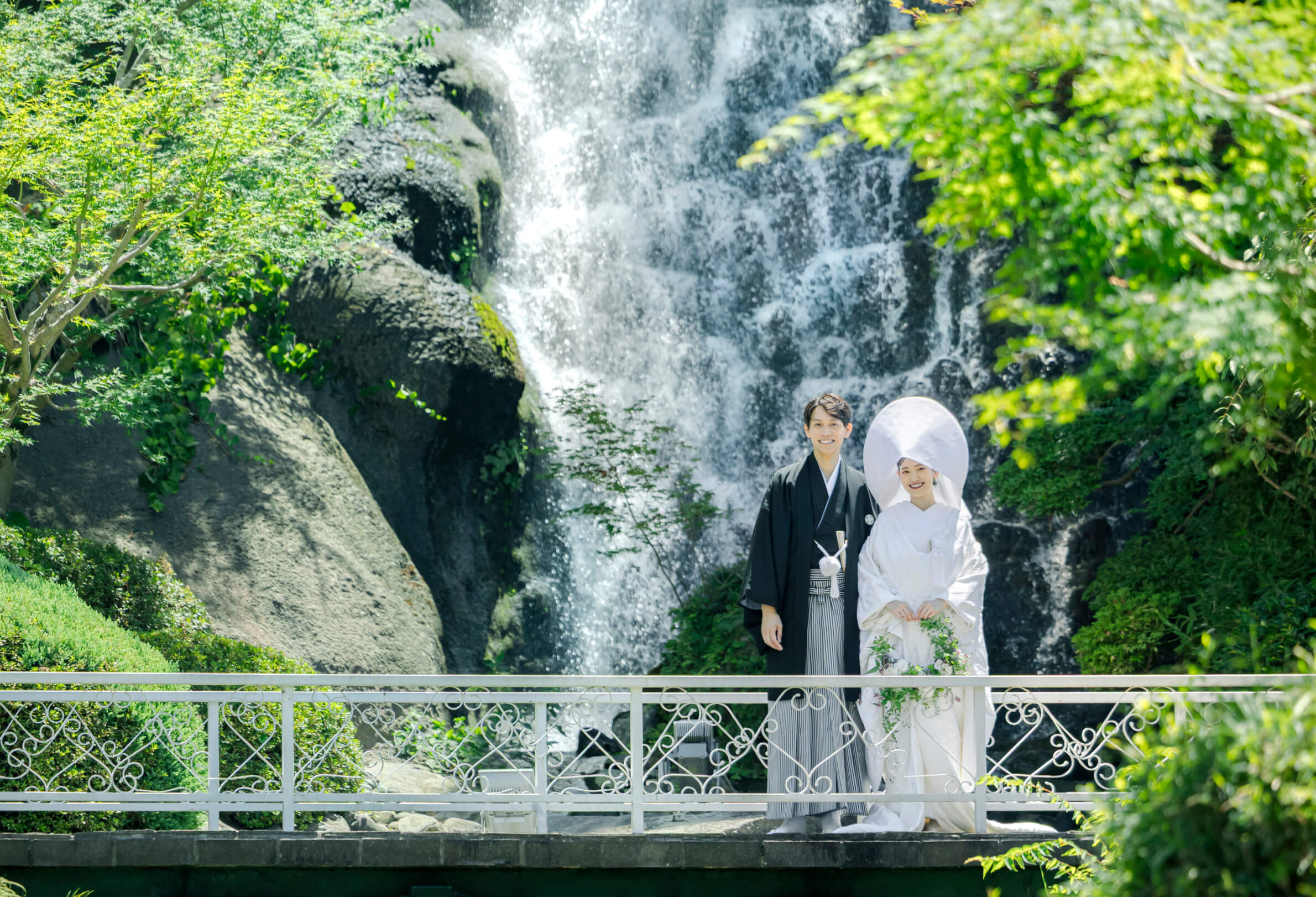 滝を背景に和装で並び立つ新郎新婦